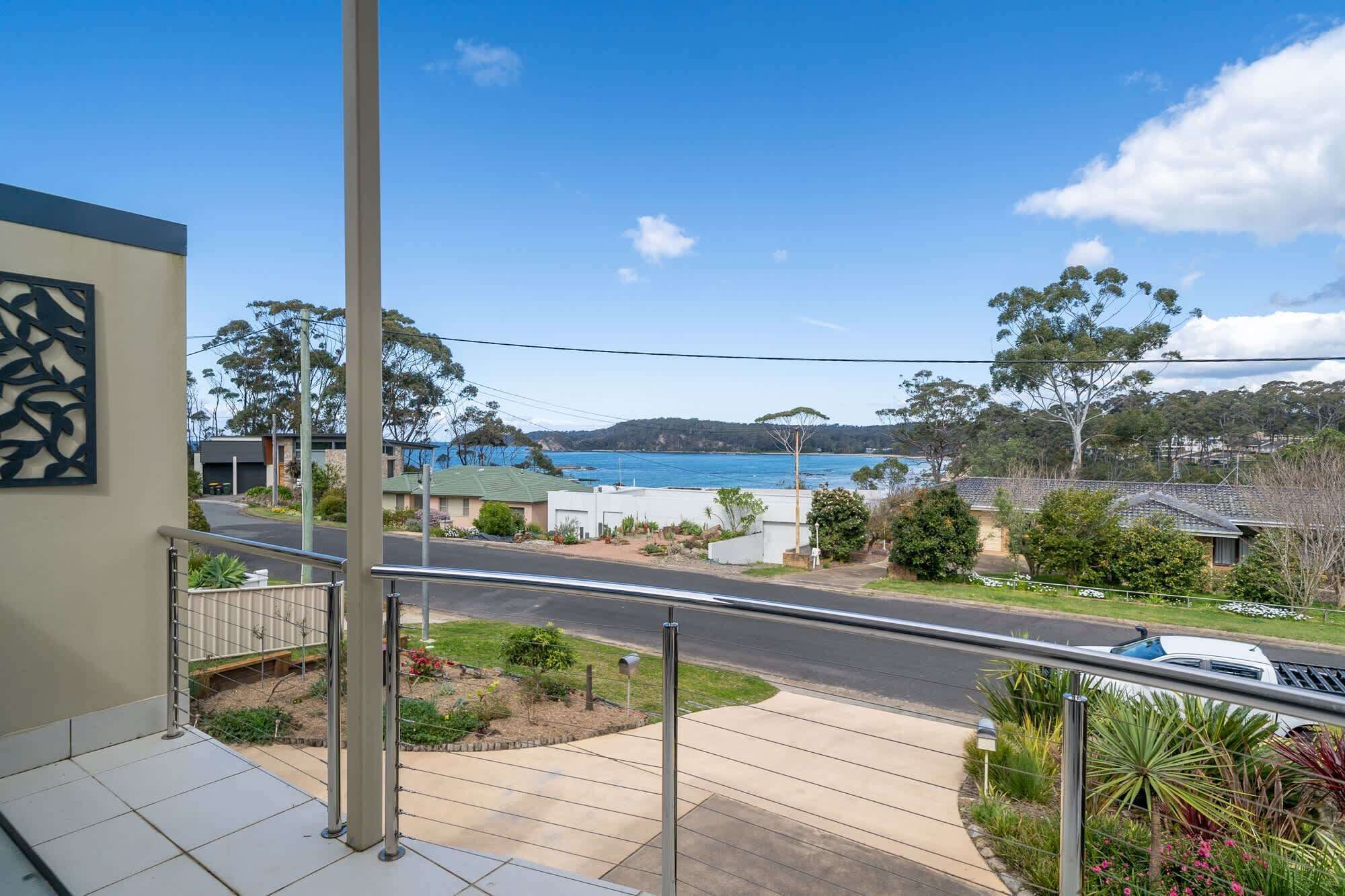 A residential area with a view of a body of water, a road, and surrounding greenery.