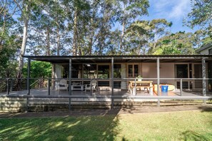 A covered outdoor area with a table and chairs, surrounded by a metal fence, and a building in the background. - Secluded 3-Bed Retreat Moments to the Beach (Surf Beach)