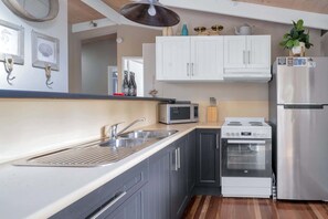A modern kitchen with a sink, microwave, stove, and refrigerator. - Secluded 3-Bed Retreat Moments to the Beach (Surf Beach)