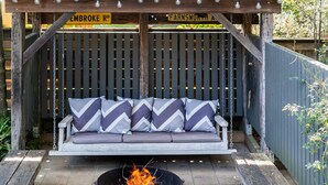 A wooden outdoor seating area with a fire pit in the center. - Secluded 3-Bed Retreat Moments to the Beach (Surf Beach)