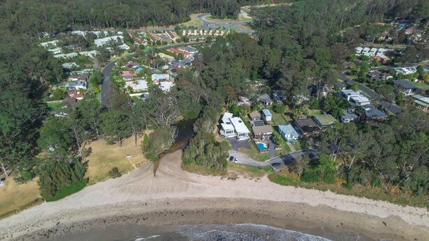 An aerial view of a coastal residential area with houses, a beach, and a road. - Secluded 3-Bed Retreat Moments to the Beach (Surf Beach)