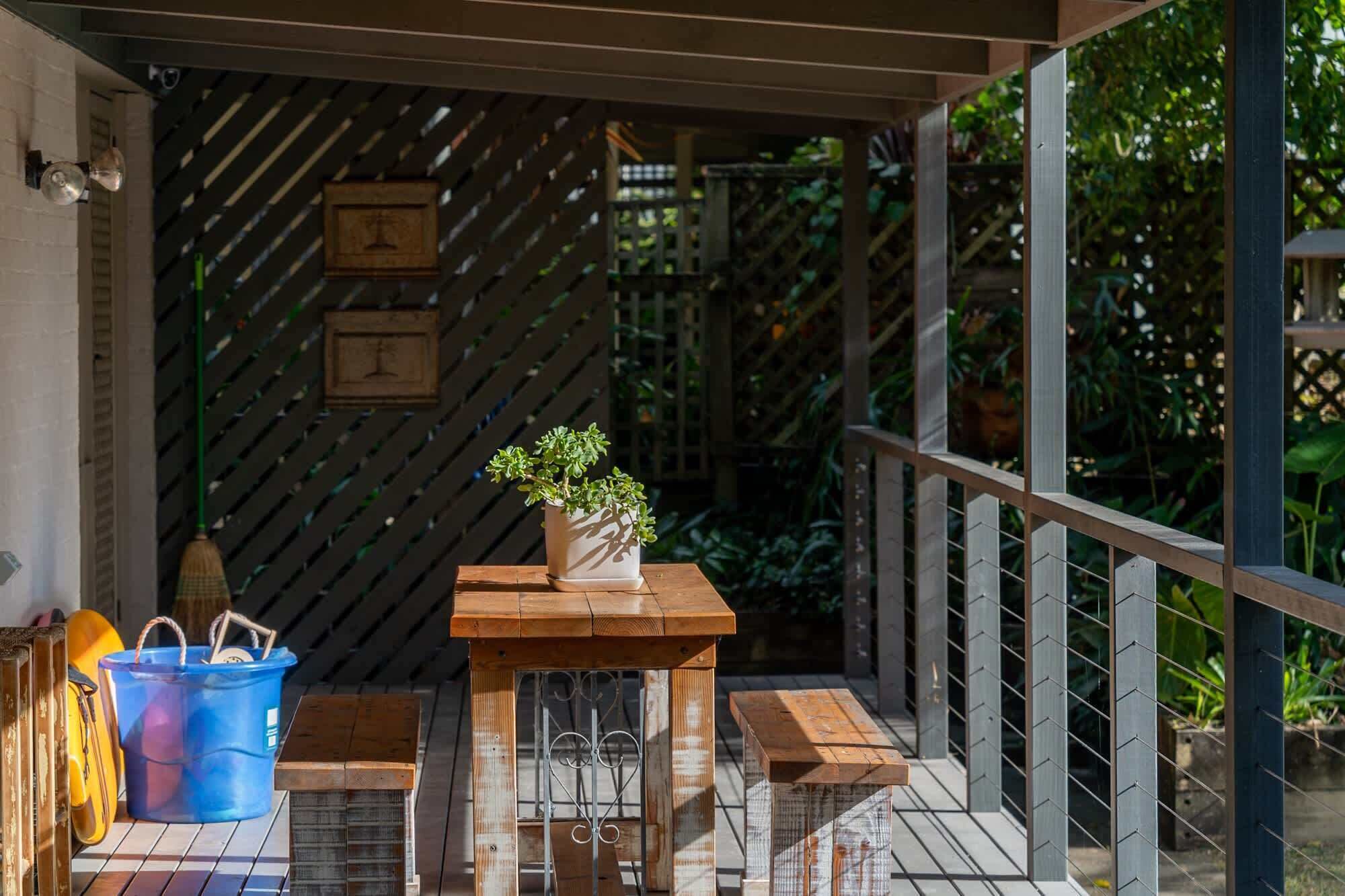 A wooden deck with a table and benches, surrounded by a metal railing.