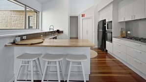 Une cuisine moderne avec un îlot central en bois, des tabourets de bar blancs et une grande fenêtre.