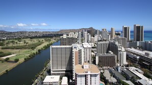 Un hôtel de grande hauteur, avec de nombreux étages, une rivière au premier plan et un paysage urbain en arrière-plan.