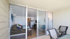 Une chambre moderne dotée d’une porte-fenêtre coulissante donnant sur un balcon, d’une petite table avec une chaise et d’un lit avec des oreillers.