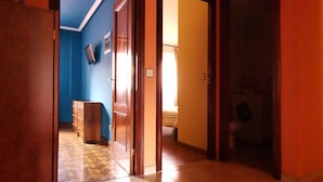 Un hall d’entrée spacieux, doté d’un sol carrelé, d’une armoire en bois et d’un mur bleu orné d’un téléviseur.