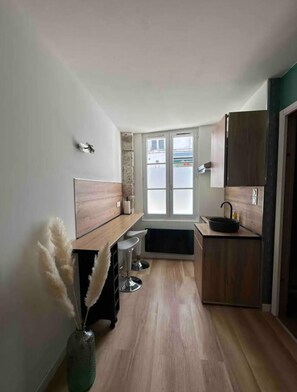 Eine moderne Küche mit Holzausstattung, einem schwarzen Spülbecken und einem Fenster mit Milchglas.