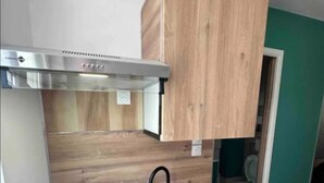 A compact kitchen with a built-in stove, a black sink, and wooden cabinets. - Studio Hypercentre Orléans, Entre Bord de Loire et Cathédrale (Orléans)