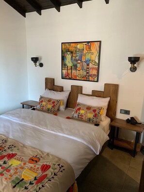 A bedroom with a bed, two nightstands, a wall-mounted lamp, and a colorful abstract painting. - Chakra (Ayvacik)