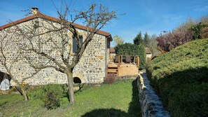 Un edificio de piedra con una terraza de madera y un pequeño jardín.