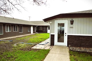 A row of single-story buildings with a central door and a small garden area.