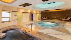 A spa area with a hot tub, lounge chairs, and a pool.