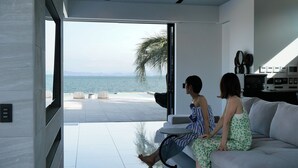 A modern living room with a large glass door leading to a pool area with a view of the sea. - PLATINUM RESORT 1 Villa with Infinity Pool with Private Beach Water Bike Boat unloading available (bring your own) Vacation Rental (大津市)