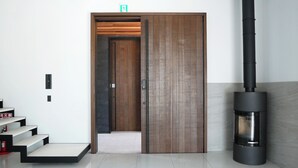 A modern interior with a wooden door, a black fireplace, and a staircase with a red fire extinguisher. - PLATINUM RESORT 1 Villa with Infinity Pool with Private Beach Water Bike Boat unloading available (bring your own) Vacation Rental (大津市)