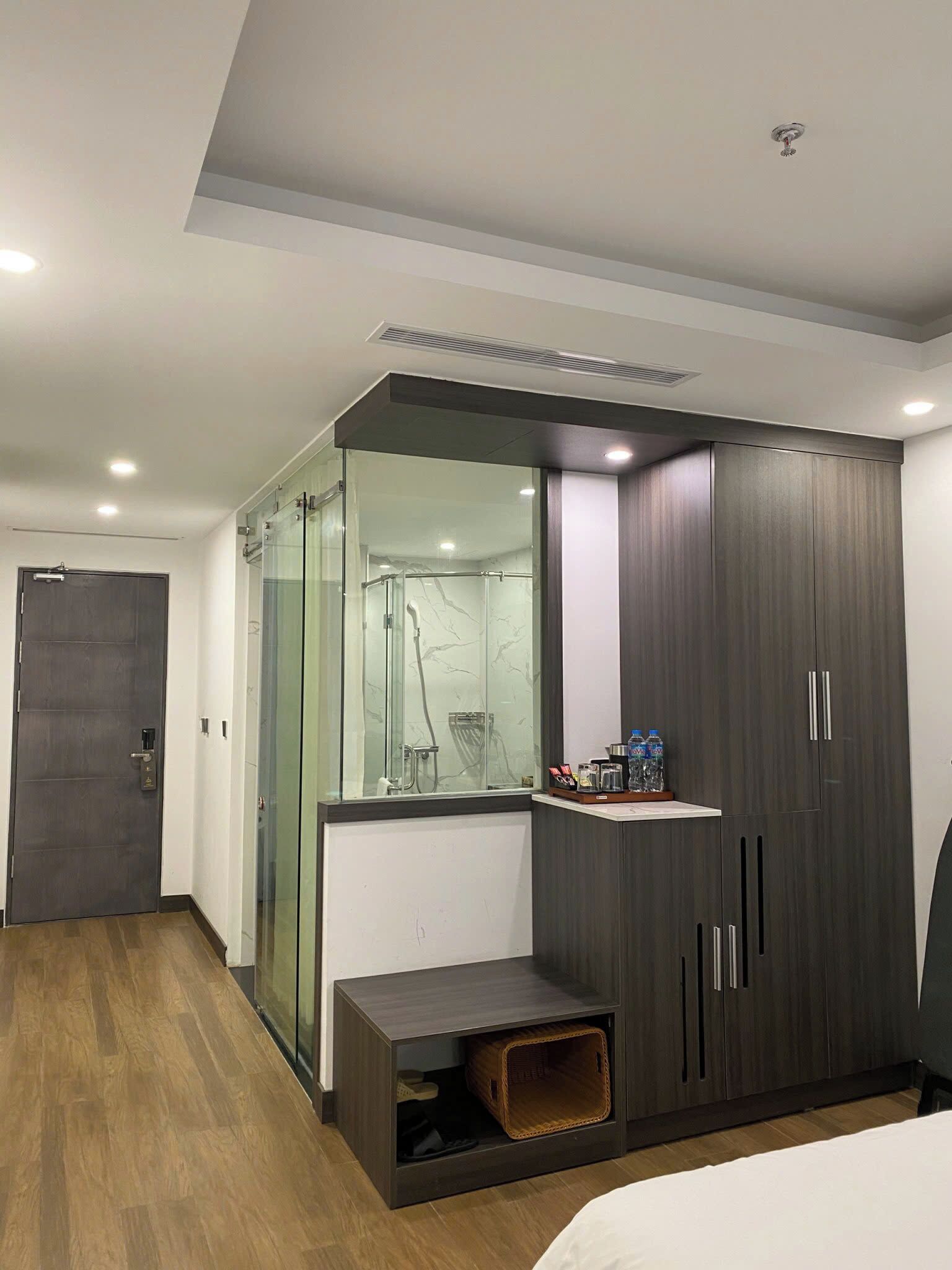 A modern bedroom with a wardrobe, a glass shower enclosure, and a bedside table.