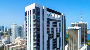 Un immeuble moderne de grande hauteur, doté de nombreux balcons et offrant une vue dégagée sur le paysage urbain environnant.