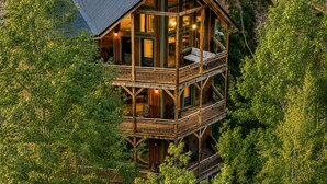 A multi-story wooden cabin with balconies, surrounded by dense greenery. - Private Indoor Pool + Hot Tub + Sauna + Theater + Game Room | Mins to Gatlinburg (Gatlinburg)