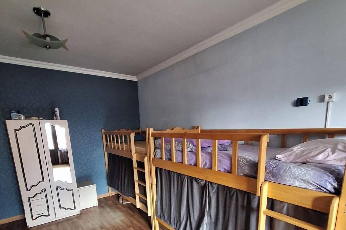 A room with two bunk beds, a wardrobe, and a ceiling fan.