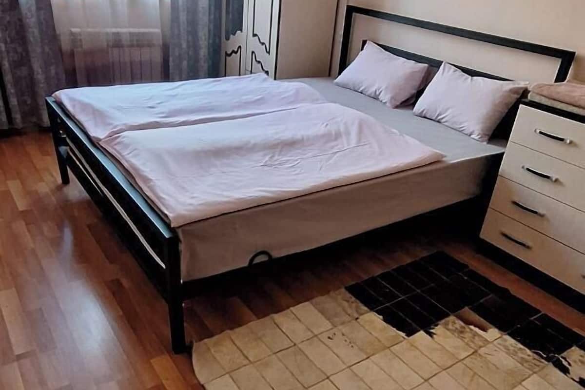 A bedroom with a bed, a bedside table, a wardrobe, and an air conditioning unit.