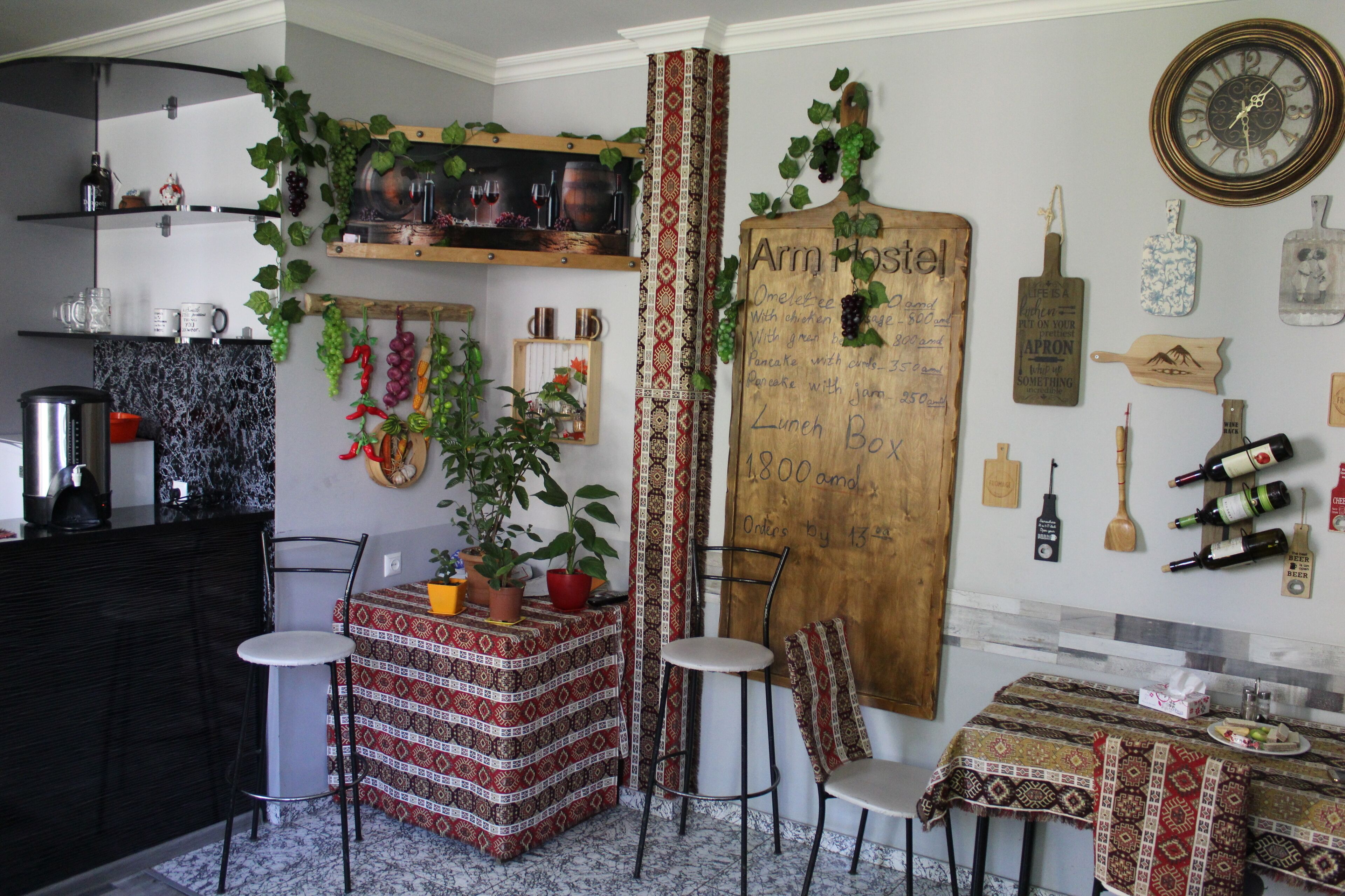 A kitchen with a wooden board displaying breakfast options, a clock, and various kitchen utensils.