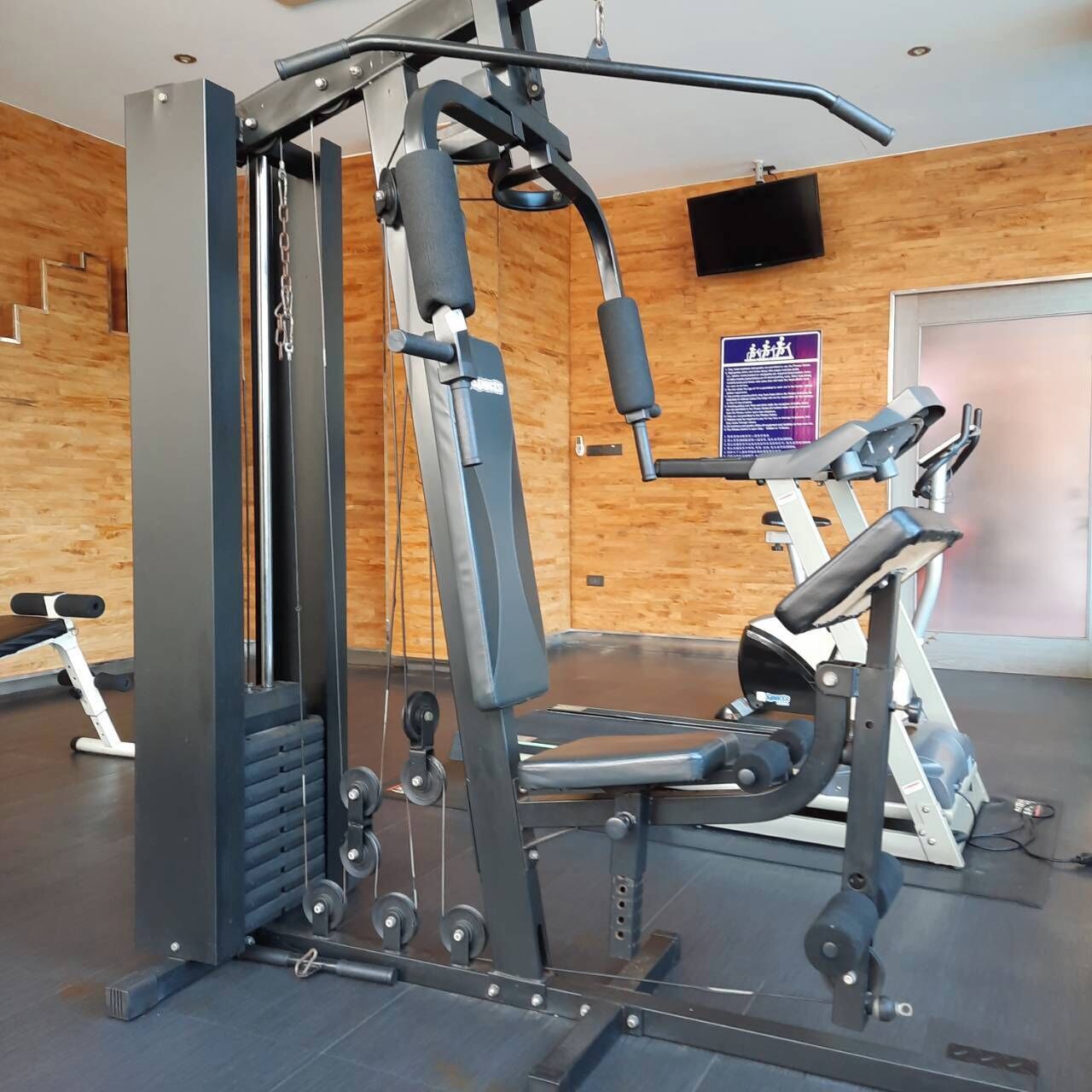 A gym with a weight machine, a bench, and a treadmill.