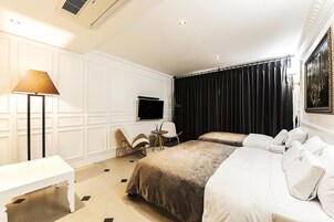 Habitación de hotel con dos camas, un escritorio, una silla, un televisor y un amplio ventanal con cortinas.