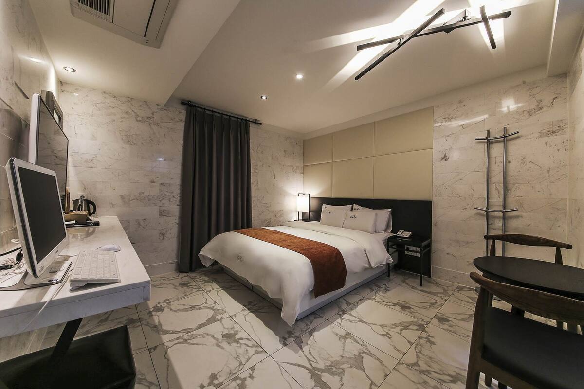 A modern hotel room with a bed, desk, and chair.