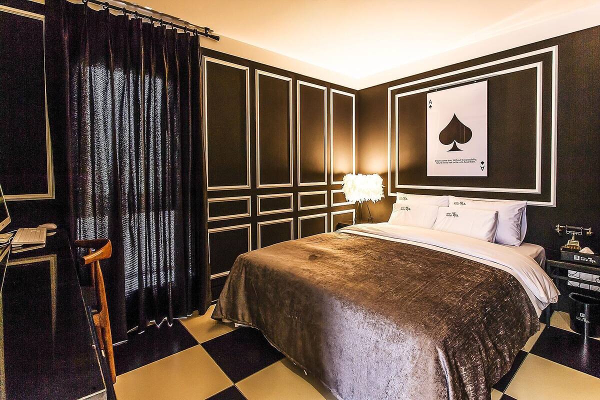 A hotel room with a large bed, a desk with a computer, and a chair.