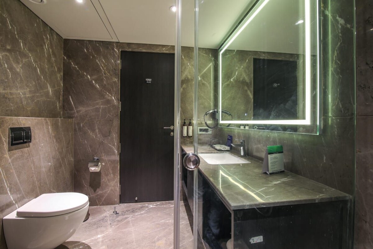 Un baño moderno con cabina de ducha de vidrio, lavamanos de mármol y un inodoro.