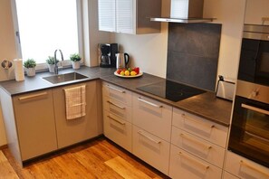A modern kitchen with a stainless steel sink, a built-in stove, and a coffee maker.