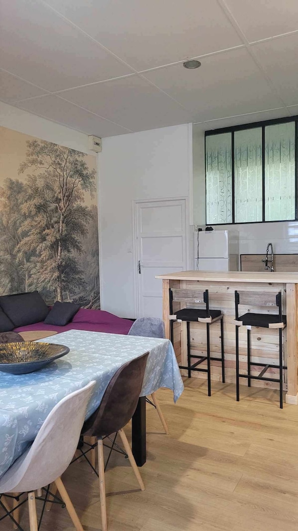 Un espace de vie compact comprenant un coin repas, une kitchenette et une fresque murale.