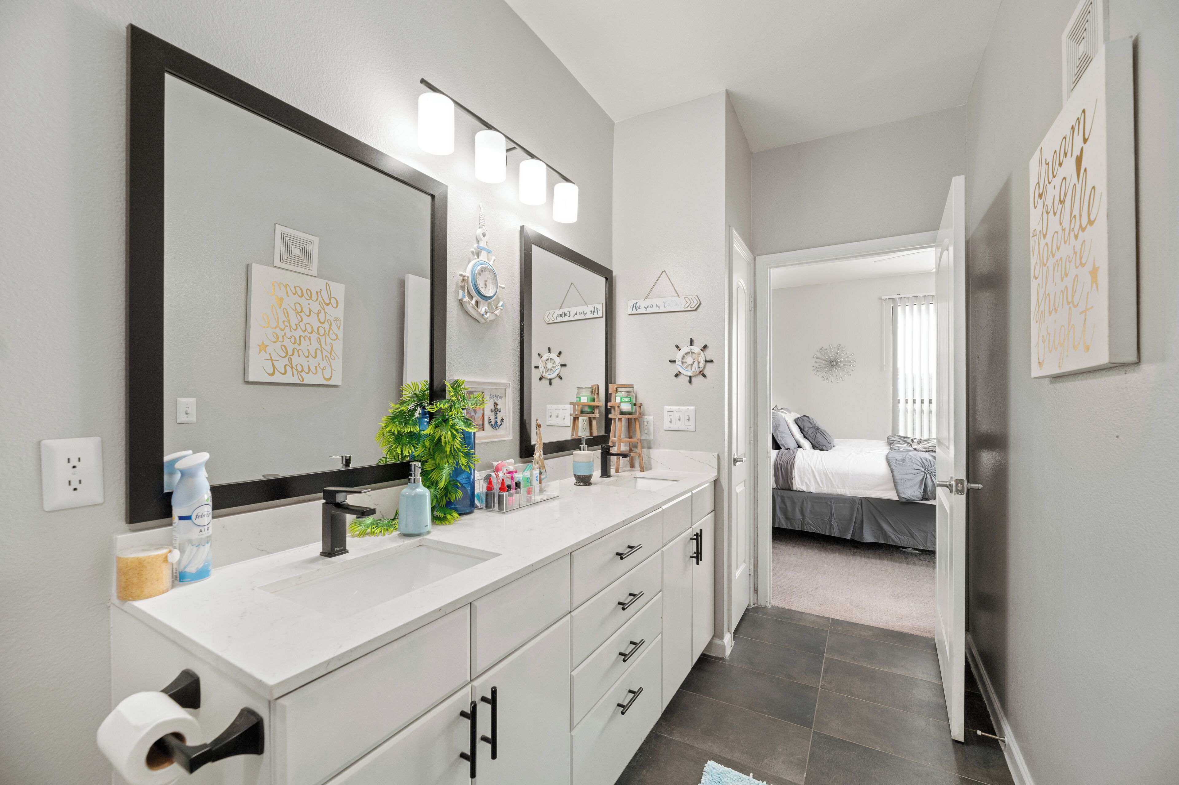 A modern bathroom with a large mirror, two sinks, and a shower area.