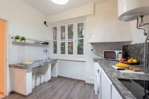 A modern kitchen with white cabinets, a built-in microwave, and a window with a view of greenery. - Cozy Maria Apartment in Portofino (Portofino)