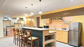 A modern kitchen with a central island, bar stools, stainless steel appliances, and pendant lighting.