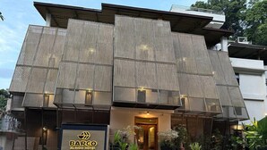 A modern hotel with a unique architectural design, featuring a prominent entrance and a well-maintained outdoor area with plants.