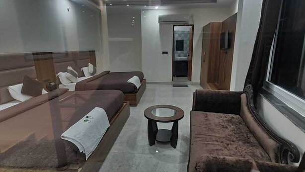 A modern living room with two sofas, a coffee table, and a large window. - JSR Hotels (Narendranagar)