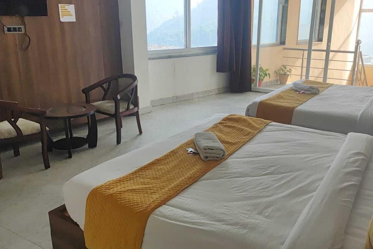 A hotel room with two beds, a desk, and a chair.
