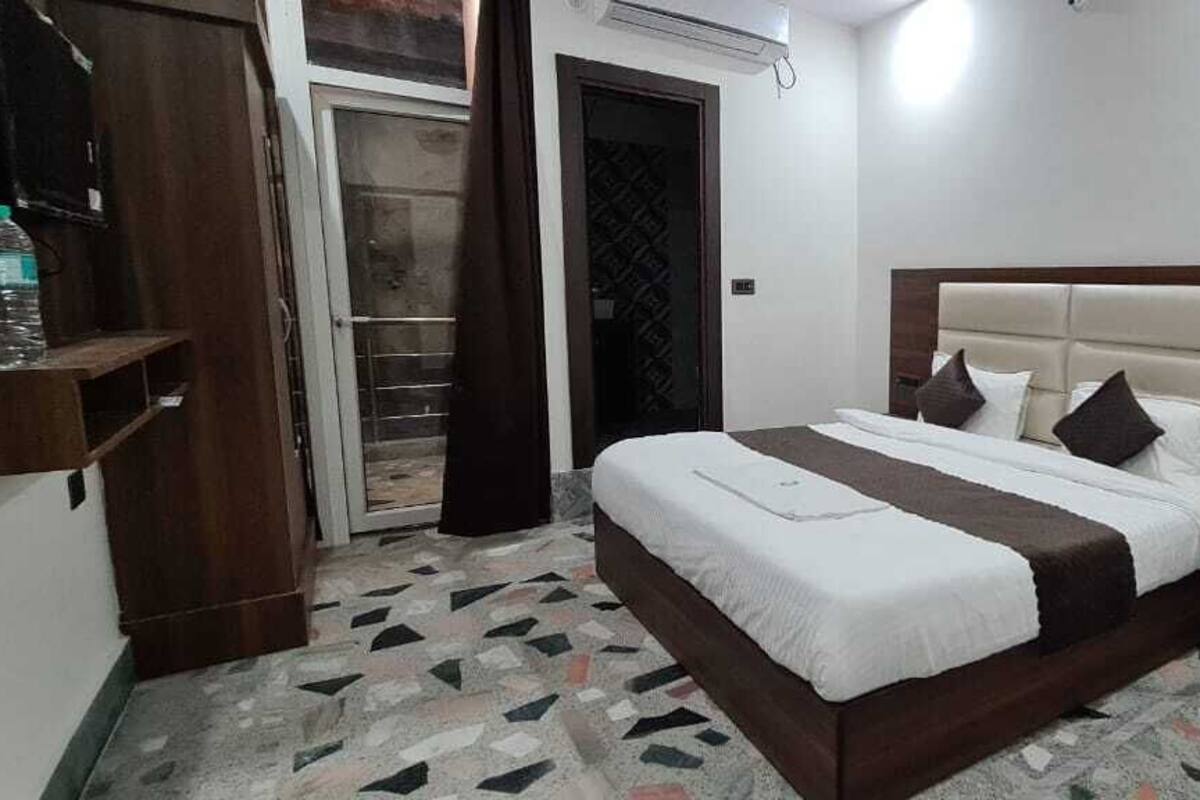 A hotel room with a bed, a chair, a nightstand, and a door.