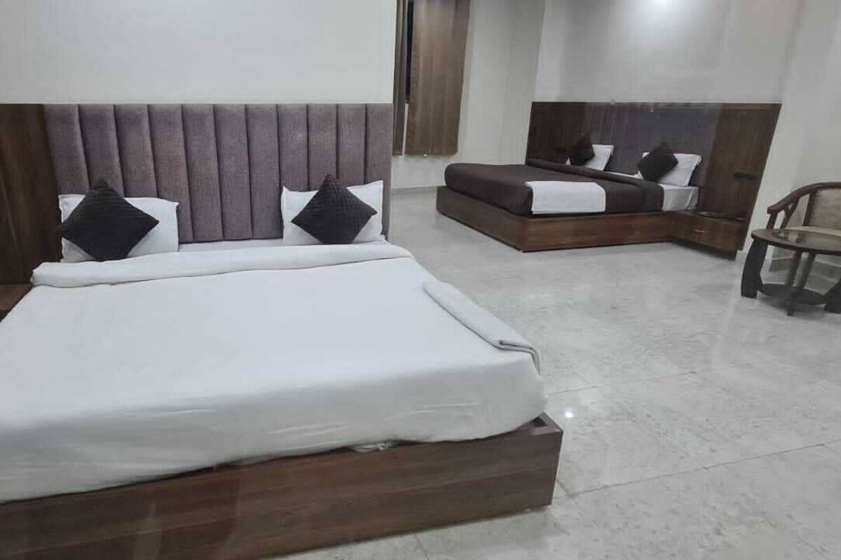 A hotel room with a large bed, a smaller bed, a desk, and two chairs.