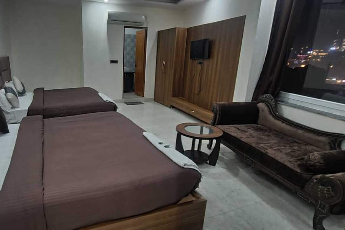 A modern living room with a sofa set, a small round table, and a TV mounted on a wooden wardrobe.
