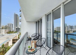 A balcony with a table, chairs, and a view of a cityscape and water. - Spectacular Resort, Prime Location, Balcony, Gym (Hallandale Beach)