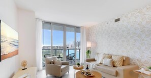A modern living room with a sofa, armchairs, a coffee table, and a view of the city through large windows. - Spectacular Resort, Prime Location, Balcony, Gym (Hallandale Beach)