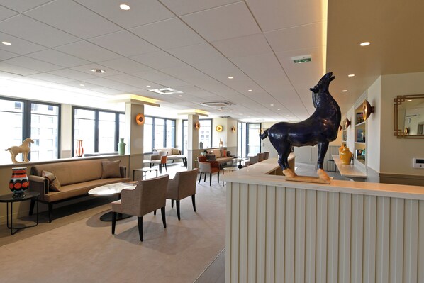 Eine moderne Hotelhalle mit Rezeption, Sitzgelegenheiten und großen Fenstern.
