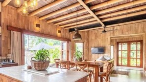 Una habitación amplia con techo de madera, una gran mesa de comedor y un televisor montado en la pared.