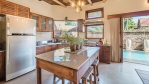 Una cocina con armarios de madera, una isla grande y vista a una piscina.