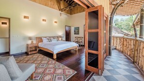 Un dormitorio amplio con una cama grande, vigas de madera en el techo y vistas al exterior.