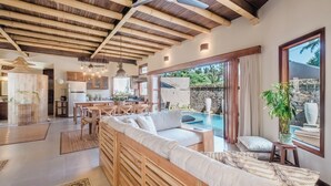 Amplia sala de estar con techo de madera, piscina y comedor.