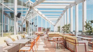 Una terraza en la azotea con mobiliario exterior, ventanas amplias y una vista despejada del horizonte de la ciudad.