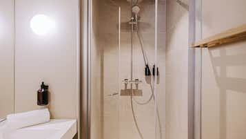 Une salle de bain moderne avec une douche à parois de verre, un lavabo blanc et une serviette.