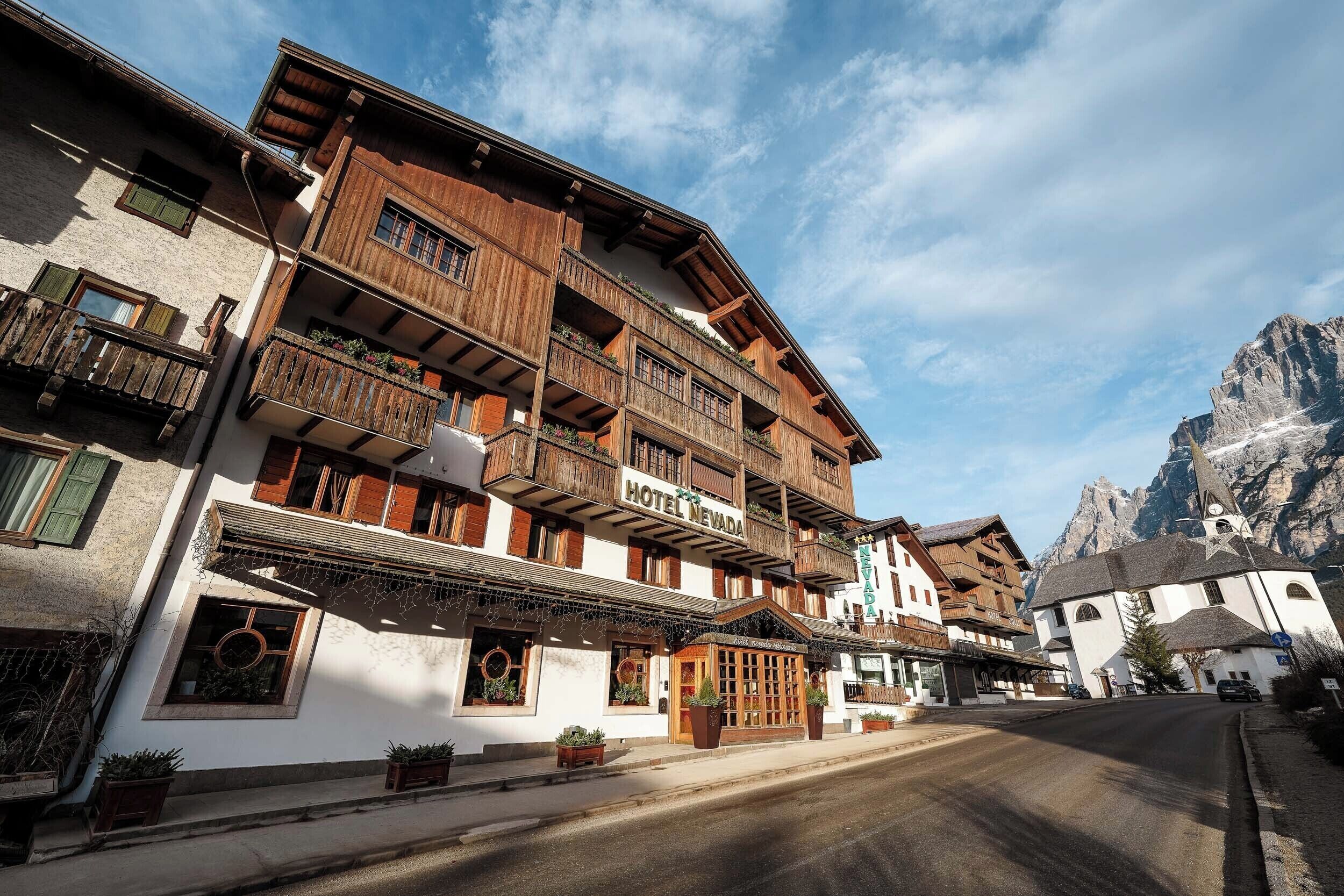 Un hôtel à la façade en bois, doté de balcons et surplombant un paysage montagneux.